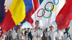 Athletes in uniform carrying flags during a ceremonial event, with the Olympic rings flag prominently displayed. The scene showcases a celebration of diversity and unity at a sporting event related to the Paralympic Games Classification.