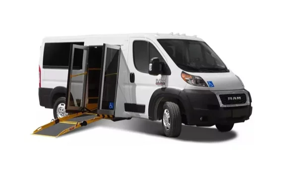 A white RAM van with an accessible ramp extended from the side entrance, designed for wheelchair access. The van is parked on a white background.