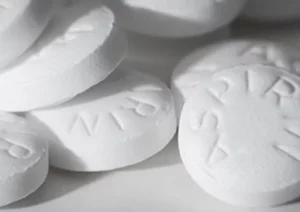 Several white, round tablets displayed on a light surface, some with stamped letters visible on their surfaces.