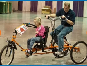 A man and a small girl riding an orange bicycle, smiling as they share a fun moment together.