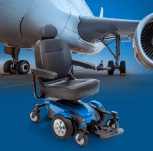 A blue power wheelchair positioned in front of an airplane, showcasing its design against a backdrop of aircraft parts, highlighting its suitability for travel.