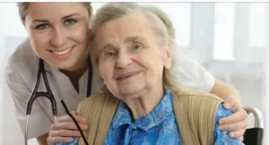 A senior woman in a blue blouse smiles while sitting in a wheelchair, with a healthcare professional in a white coat and stethoscope behind her, both appearing friendly. This image reflects care associated with Northland Care Health Products.