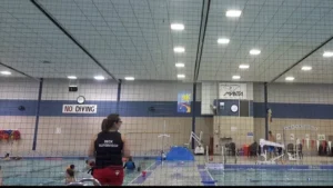 2 spacious indoor swimming pools filled with water while instructor standing by side