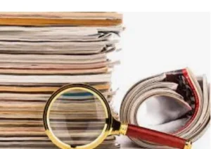 A stack of various academic documents next to a magnifying glass, with a rolled magazine partially visible, representing the examination of SCI Scholarly Documents.