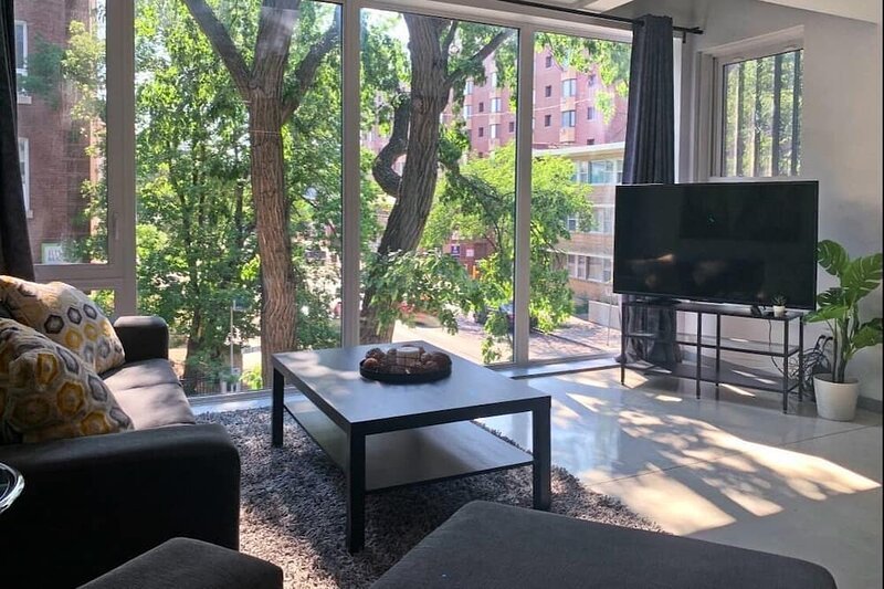 Pictures shows a vacation rental home with beautiful window and outside patio with trees in a relaxing setting