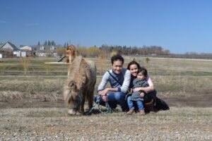 Family of three sitting beside Shetland pony where they were doing therapy with horses on the ranch