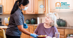 Caregiver is standing up and assisting a client sitting at her kitchen table