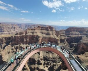Tourists visiting the Grand Canyon Skywalk, a glass bridge extending over the canyon, with stunning rock formations visible below. The scene highlights Beautiful Accessible Viewpoints in the World.