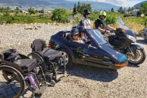 A group of people riding a motorcycle, with wheelchairs attached, showcasing inclusivity in outdoor activities.