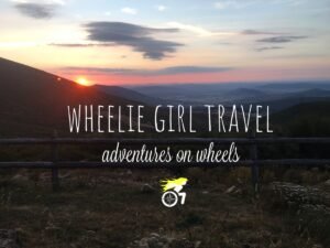 Image of a sitting sun on mountains casting an orange glow on the cloudy sky. There is also an icon depicting a woman sitting a wheelchair encouraging disable people.