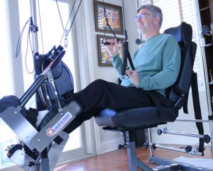A man smiling while exercising on a quadricisor exercise machine.