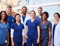 A diverse team of medical professionals standing together, smiling for a group photo in a hospital environment.