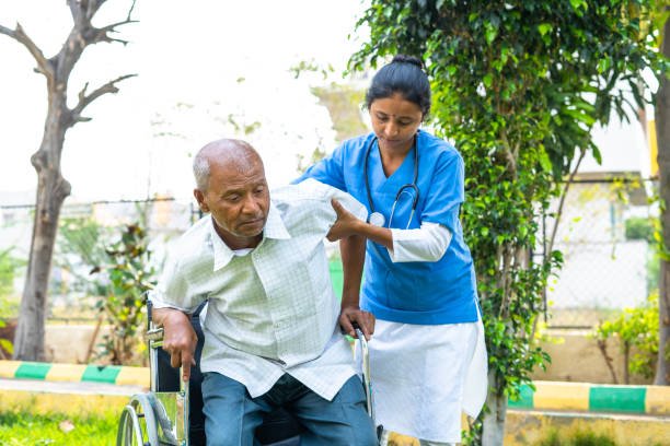 A nurse assists an elderly man in a wheelchair, providing support and care in a healthcare setting.