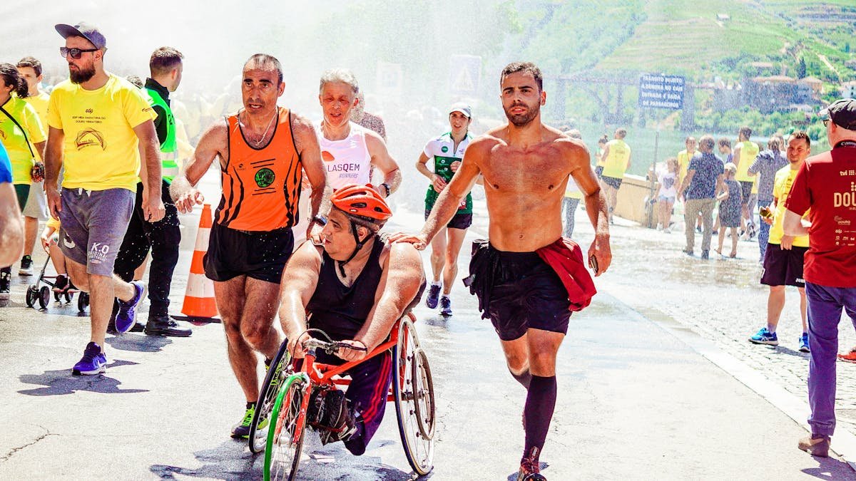 A man in a wheelchair participates in a race with several other athletes, showcasing inclusivity in sports.