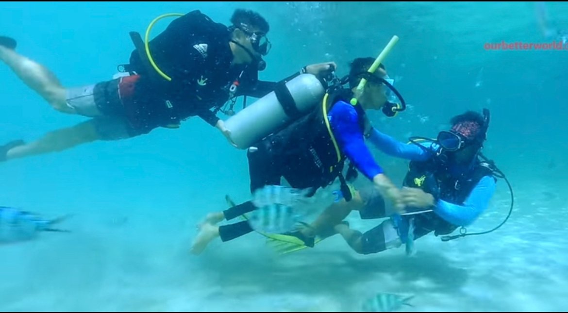 Three scuba divers in the water, showcasing an underwater adventure in a sunny, clear ocean environment.
