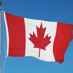 Photo of the red and white Canadian flag with the new leaf set against the blue sky