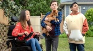Disabled girl sitting in a wheelchair is worth a couple friends, one of whom is holding a puppy dog