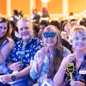 Men and women are sitting at a costume themed event with a large audience