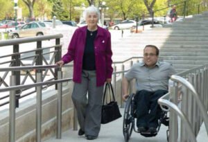 Mom is in a wheelchair outside an office building and beside circumstances a woman wearing purple sweater