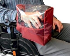 Madness sitting in a wheelchair with his right hand on the joystick and he’s got a red and clear plastic cover over his hand so he can still see his hand back. It won’t get wet.
