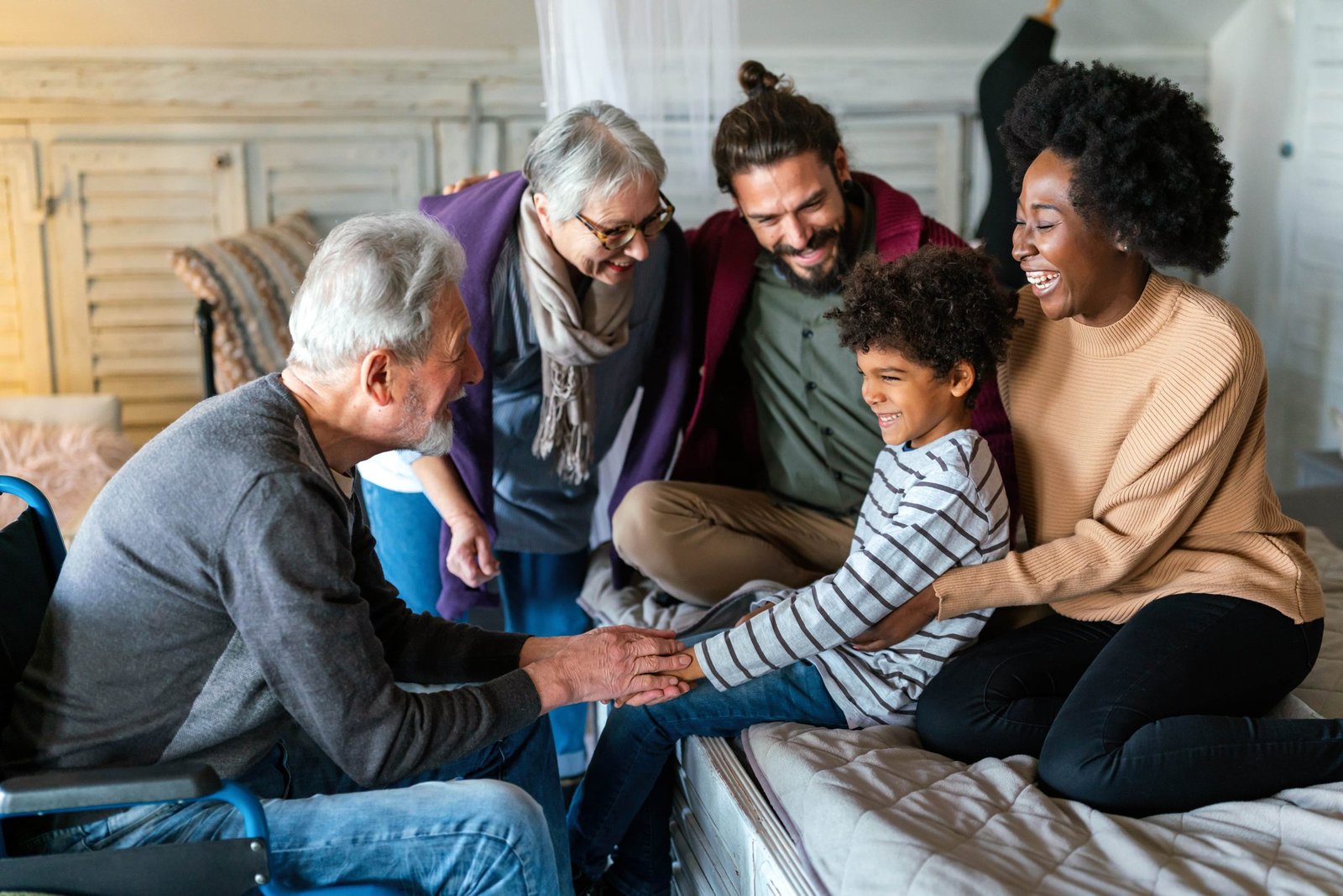 Healthcare worker is working with a young boy on edge of the bed while the family is looking on
