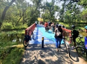 A group of cyclist as posing on a painted colourful bridge over a small river
