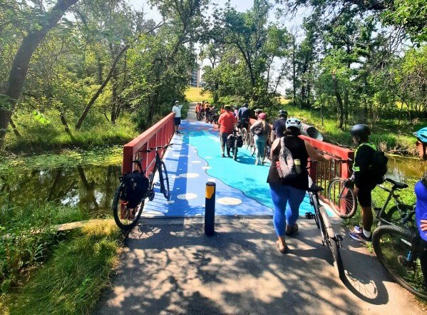 A group of cyclist as posing on a painted colourful bridge over a small river
