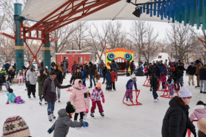 A group of skaters wearing a variety of colourful winter jackets is on the ice of the river
