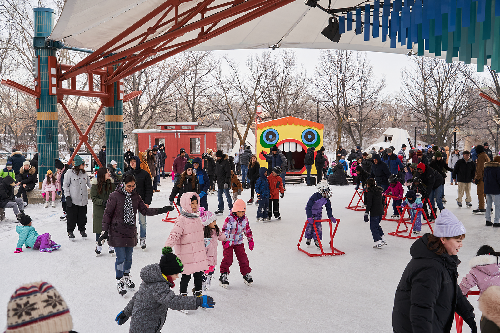 A group of skaters wearing a variety of colourful winter jackets is on the ice of the river