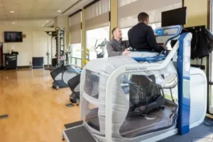Mail patient is upright inside this antigravity machine being assisted by another male therapist inside the clinic