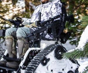 I disabled writer, Justin, White, and grey camouflage snowsuit is outside in a tractor riding on the snow