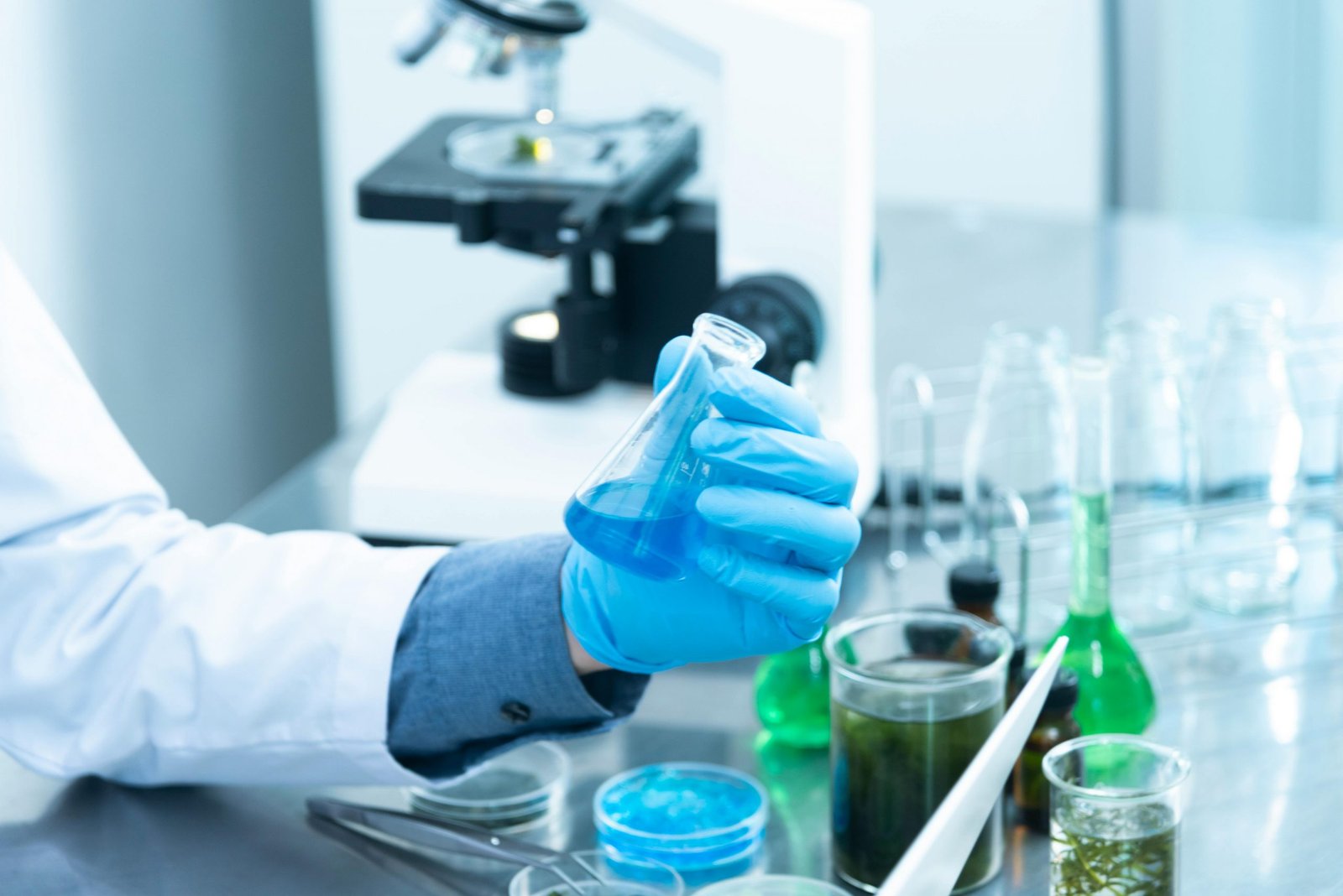 Lab technician in a white coat and blue gloves is howling two different files doing some testing in the laboratory
