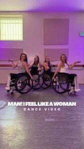 Four ladies in wheelchairs part of a dance team on the dance floor set against the purple lit up background