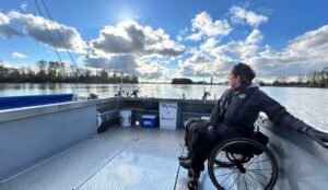 A girl sitting in wheelchair is on a boat ride & enjoying scenes around her