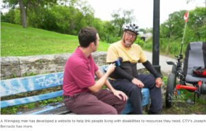 Joesph Bernacki talks to George Loewen about website in a park with red adaptive cycle beside them