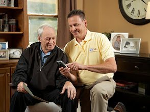 Senior man seated being assisted by male caregiver