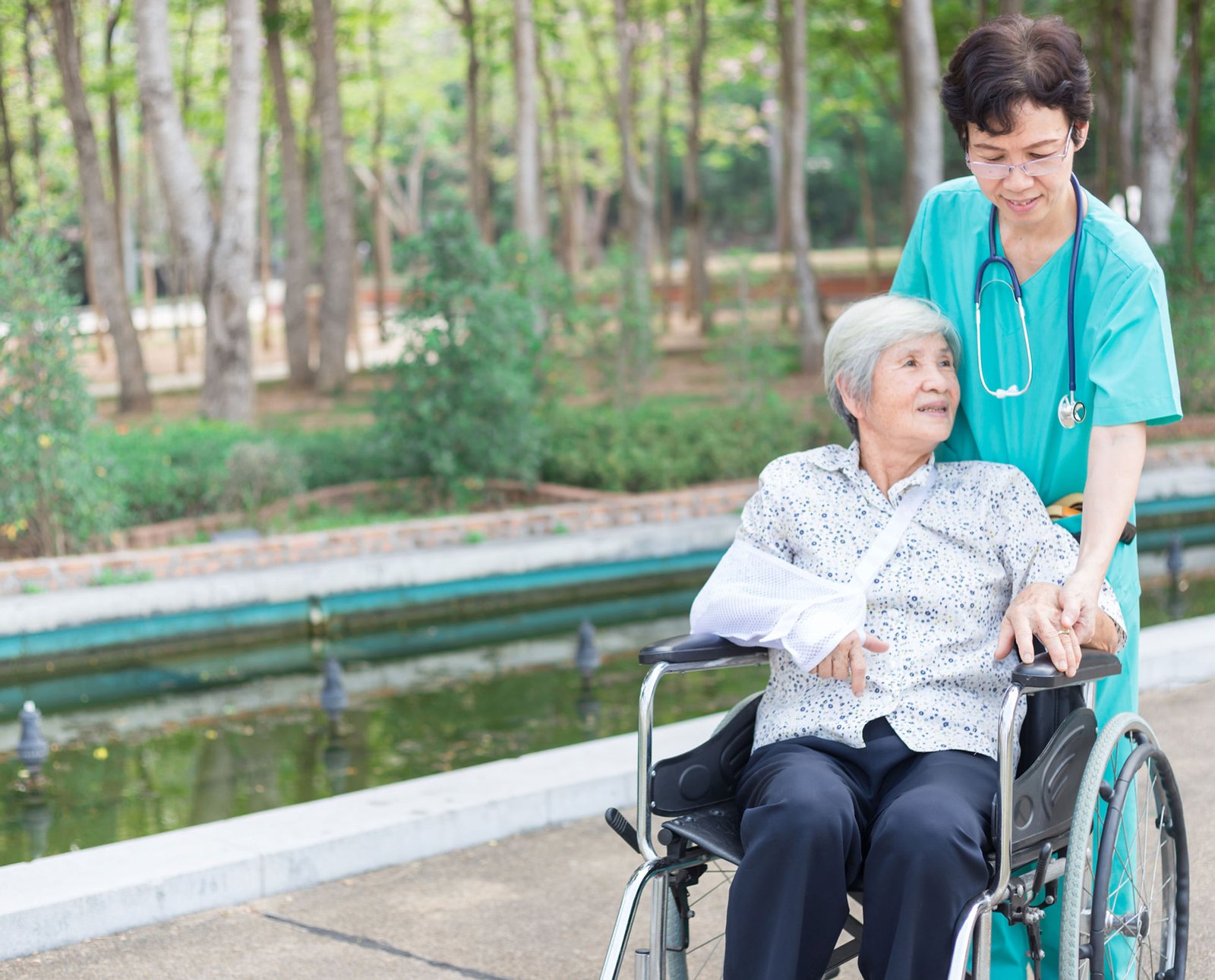 Woman in wheelchair being pushed baby healthcare aide