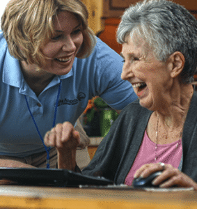 Elderly woman is being attended to by female aide in house kitchen