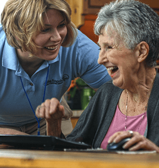 Elderly woman is being attended to by female aide in house kitchen