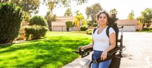 Women dressed in white is in a stand-up wheelchair on a residential street in the sunshine